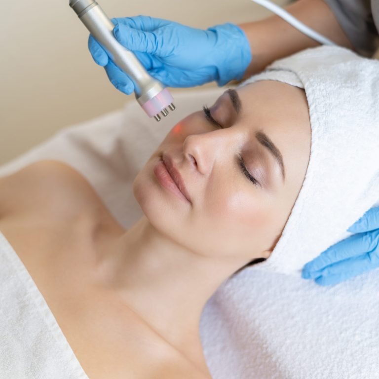 Young woman lying on cosmetologist's table during rejuvenation procedure. Cosmetologist take care about neck and face skin youthfull and wellness. Hardware face cleaning procedure